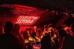 Interior del club con iluminación roja y público disfrutando de la música