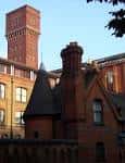 Vista exterior del edificio histórico de Bow Quarter con chimenea y torre de ladrillo