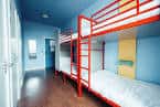 Habitación interior con literas rojas y paredes azules