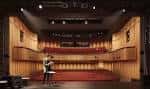 Interior del auditorio con butacas rojas y escenario iluminado