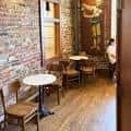 Interior acogedor de Chestnut Hill Coffee Company con mesas y sillas junto a pared de ladrillo