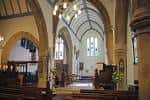 Interior de la iglesia con arcos góticos y bancos de madera