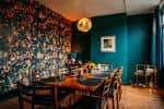 Interior del espacio GULP con decoración de pared floral y mesa de comedor