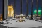 Sala de eventos con vista nocturna a la ciudad y mesa decorada para cena