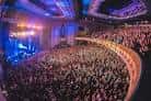 Concierto en vivo en el Eventim Apollo con luces de escenario azules y multitud en pie