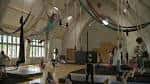 Vista general del gimnasio de entrenamiento con múltiples equipos de circo y alumnos