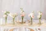 Mesa de boda decorada con jarrones pequeños y flores blancas y rosadas