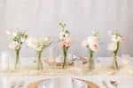 Detalle de centros de mesa con flores frescas en jarrones de vidrio para eventos