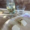 Detalle de copa de vino blanco y quesos servidos en tabla de madera