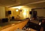 Interior del espacio de eventos con escenario y equipo de sonido