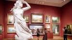 Interior del museo con escultura clásica en primer plano y salas de exposición al fondo