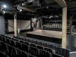 Interior del auditorio vacío con butacas negras y escenario central