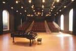 Auditorio con piano en el escenario y butacas rojas