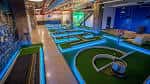 Vista interior del campo de mini golf con iluminación LED azul y obstáculos temáticos