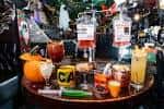 Mesa decorada con bebidas temáticas y elementos de Halloween en el bar