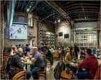 Interior del taproom de Evil Genius Beer Co. con clientes sentados en mesas