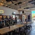 Espacio interior de 56 Brewing con mesas largas y ventiladores en el techo