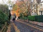 Calle arbolada del suburbio victoriano de North Oxford con hojas otoñales y personas caminando