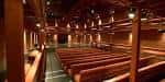 Interior del auditorio con asientos de madera y techo abuhardillado