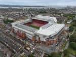 Vista aérea del estadio Anfield en Liverpool, mostrando su estructura exterior y entorno urbano