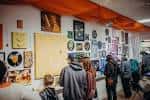 Interior del espacio con paredes llenas de arte y visitantes