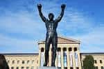 Vista frontal de la estatua de Rocky contra el cielo azul y el museo al fondo