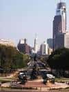 Avenida arbolada del Parkway con estatuas y skyline urbano