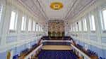 Interior del gran salón principal con butacas azules, techo decorado y órgano en el fondo