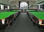 Sala de billar con mesas verdes y grandes ventanales