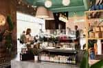 Área interior del café con estanterías, lámparas colgantes y personal trabajando