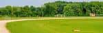 Vista panorámica de los campos deportivos rodeados de árboles en un día soleado