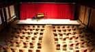 Interior del auditorio con escenario y cortinas rojas