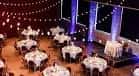 Sala preparada para evento con mesas redondas y decoración de luces