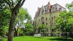 Vista exterior de un edificio histórico del campus rodeado de árboles y césped verde