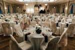Salón principal decorado para una boda con mesas redondas y sillas cubiertas