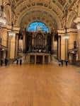 Interior de la Great Hall mostrando el suelo de madera pulida, el arco abovedado decorado y el órgano en el fondo