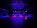 Sala de eventos vacía con iluminación ambiental en tonos púrpura y rosa, ideal para fiestas o recepciones