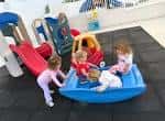 Niños jugando en un área de juegos interior con tobogán y balanza