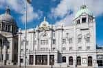 Vista exterior del His Majesty's Theatre en Aberdeen con su fachada neoclásica blanca y cúpulas bajo un cielo azul