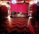 Escenario principal con cortinas rojas y pista de baile vacía lista para eventos