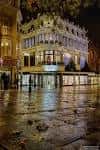 Vista nocturna del edificio Jarrolds iluminado bajo la lluvia, reflejando luces en el pavimento