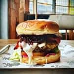 Plato principal: hamburguesa gourmet servida en mesa con fondo desenfocado