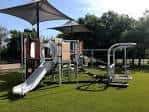 Área de juegos al aire libre con toboganes y estructuras de sombra