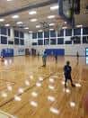 Pista deportiva interior con canchas de baloncesto y personas jugando