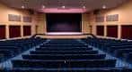 Interior del auditorio principal con butacas azules y escenario
