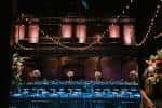 Interior del auditorio decorado para una boda, con mesas iluminadas y luces colgantes