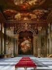 Sala de banquetes interior con techo pintado al fresco y alfombra roja ceremonial