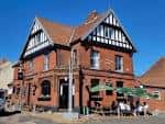 Vista exterior del pub Marlborough Arms en Norwich con fachada de ladrillo rojo y detalles arquitectónicos Tudor
