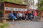 Grupo de personas sentadas frente al letrero 'Welcome to Kilby Court'