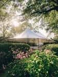 Jardín trasero con carpa blanca instalada para evento al aire libre